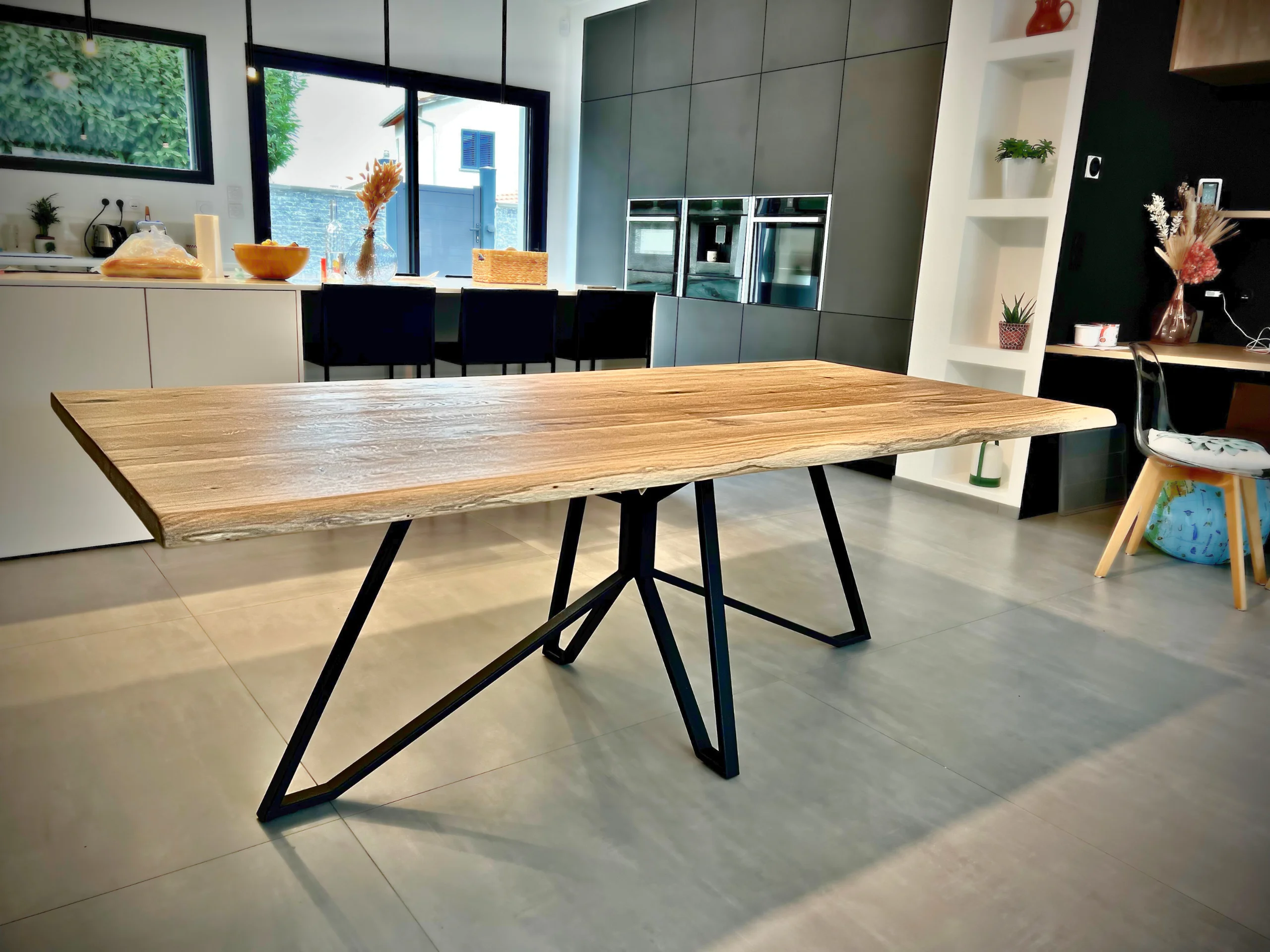 A wooden table with a central steel spider table leg