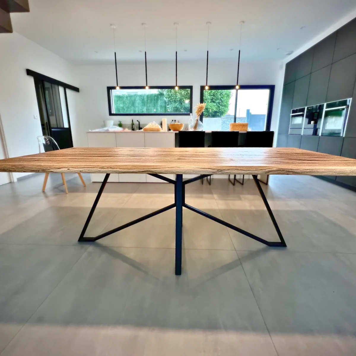 Une table à manger avec un pied graphique Spider en acier noir dans une salle à manger