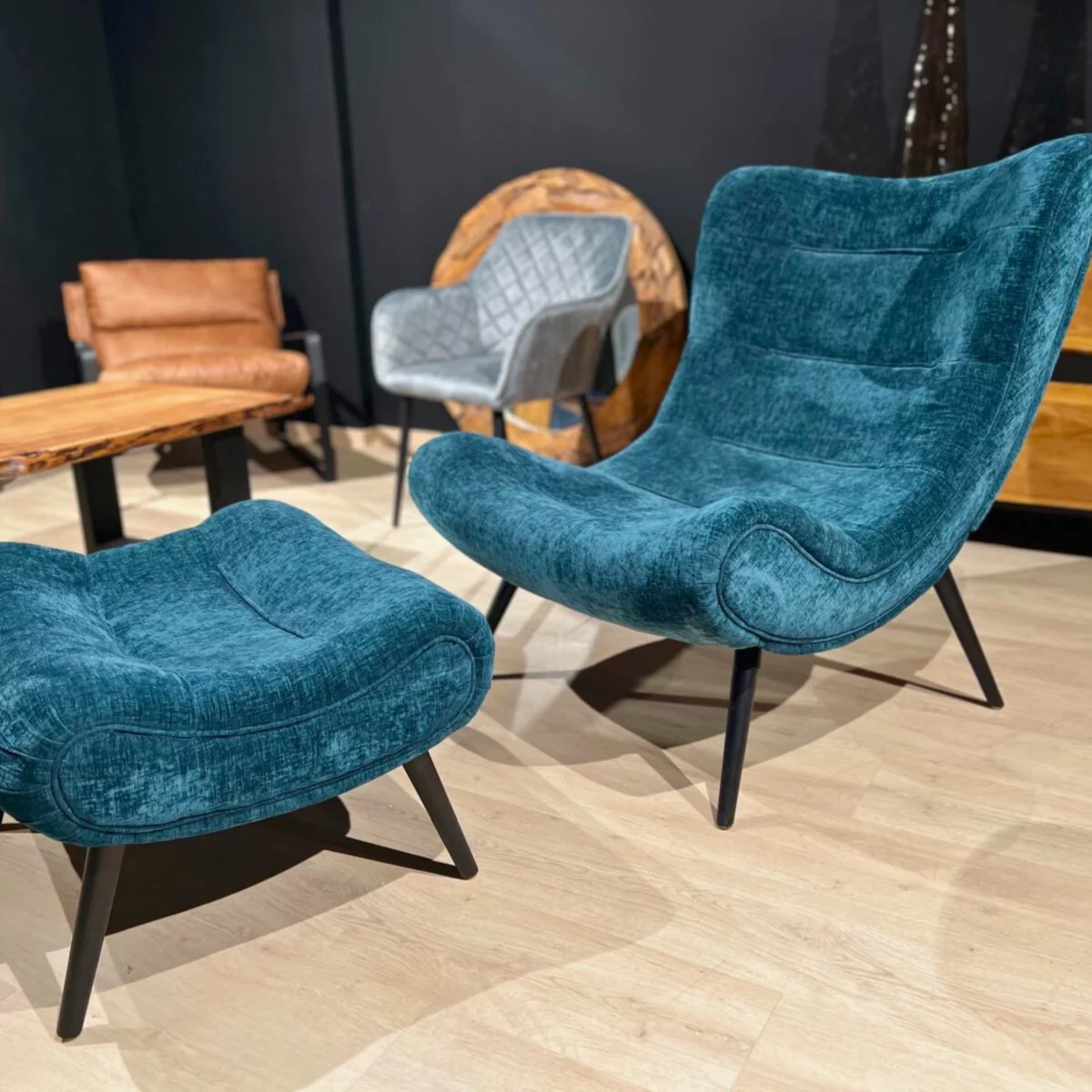 Un fauteuil en velours bleu canard avec un repose pied