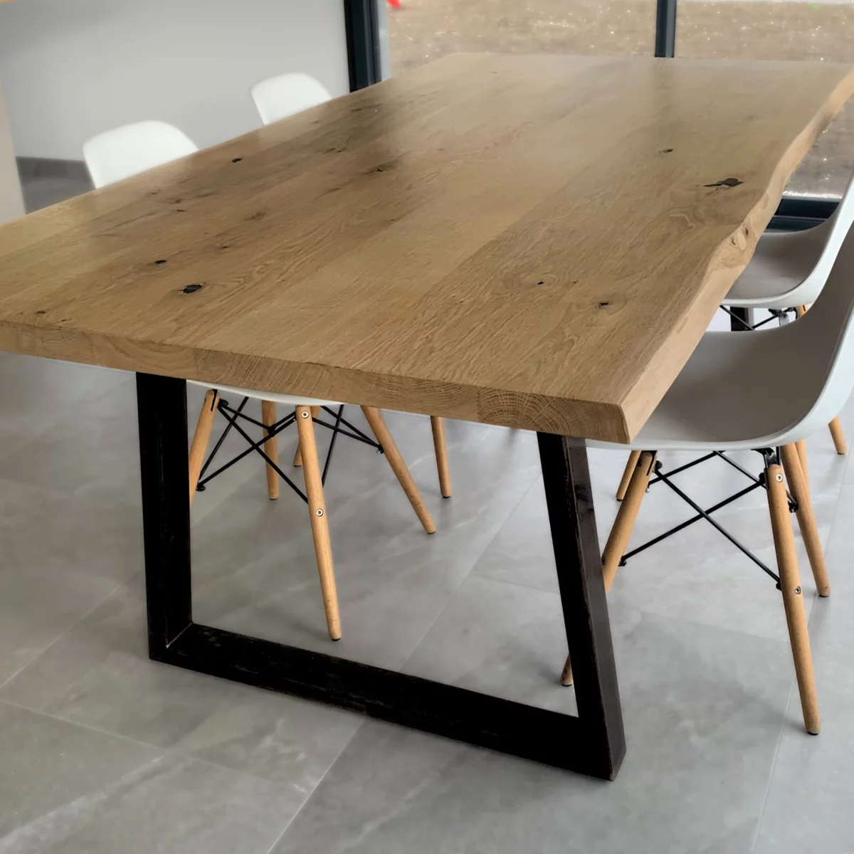 Une table avec un pied table en acier noir en forme de trapèze