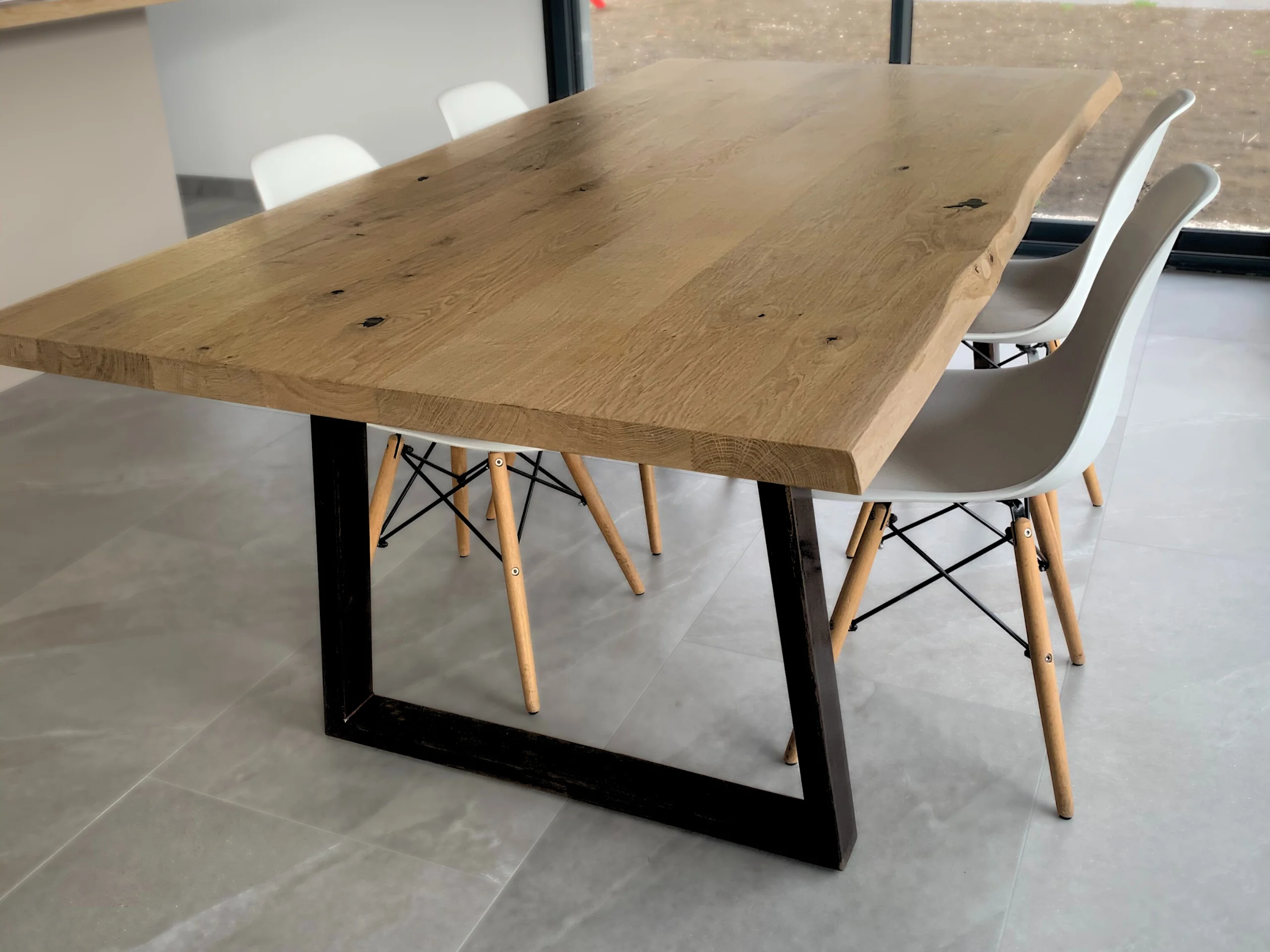 Une table avec un pied table en acier noir en forme de trapèze