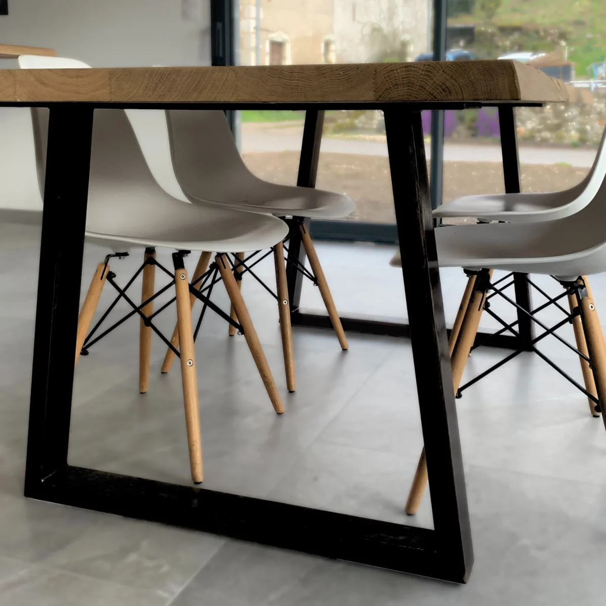 Une table avec des pieds en acier en forme de trapèze