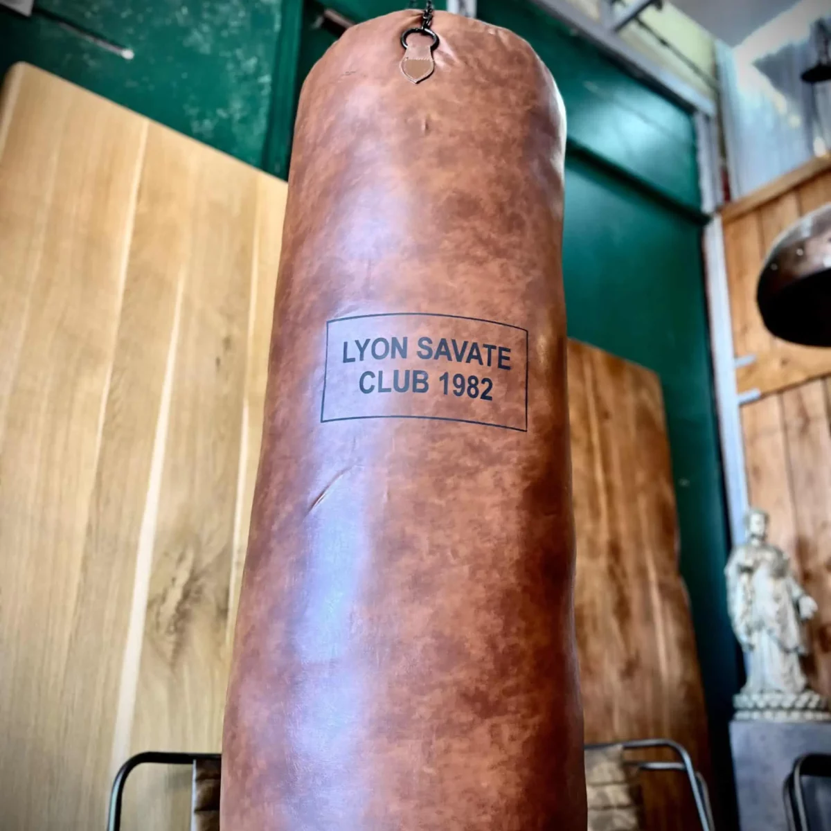 Un sac de boxe vintage avec l'inscription "Lyon savate club 1982"