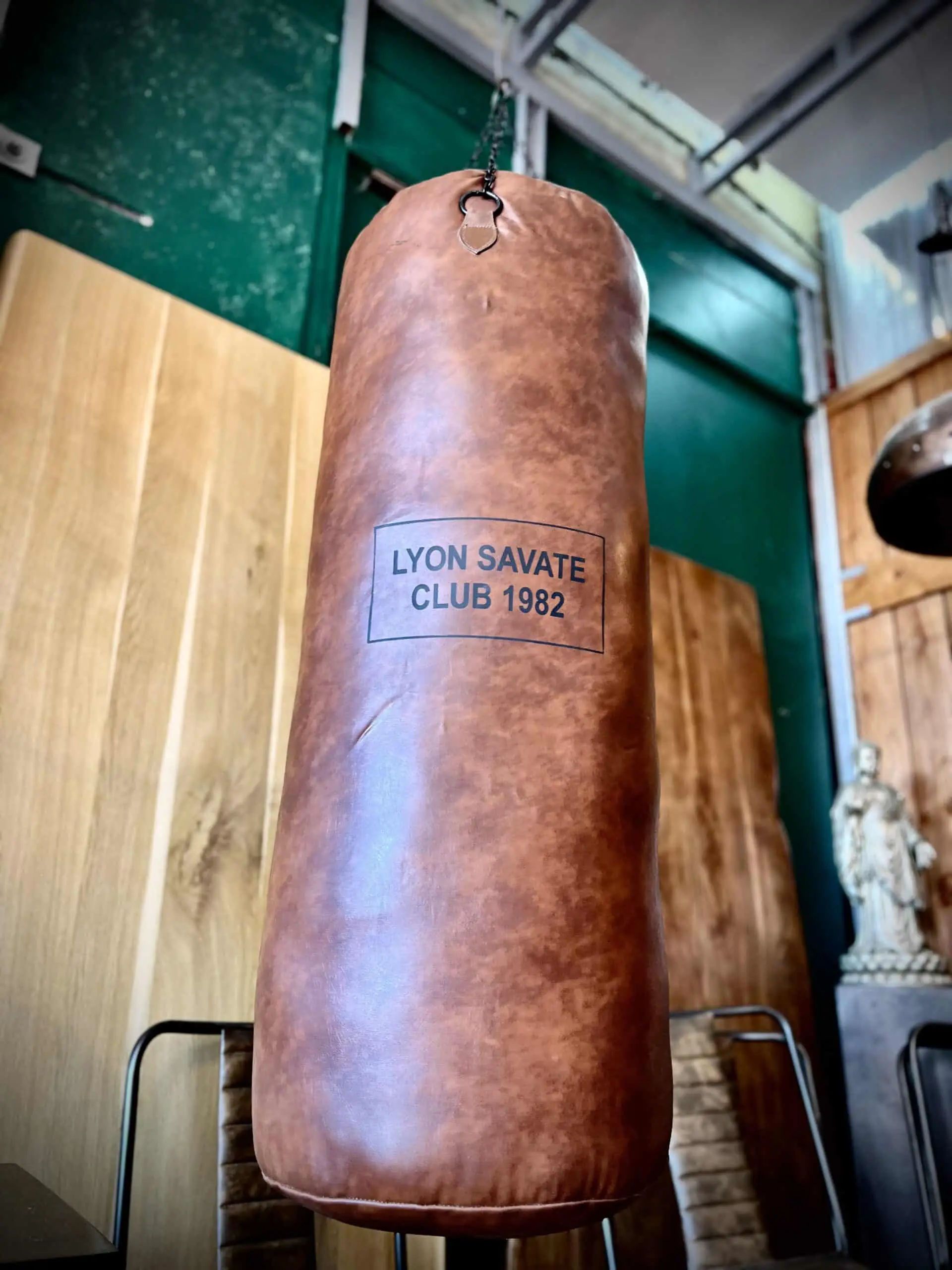 Un sac de boxe vintage avec l'inscription "Lyon savate club 1982"