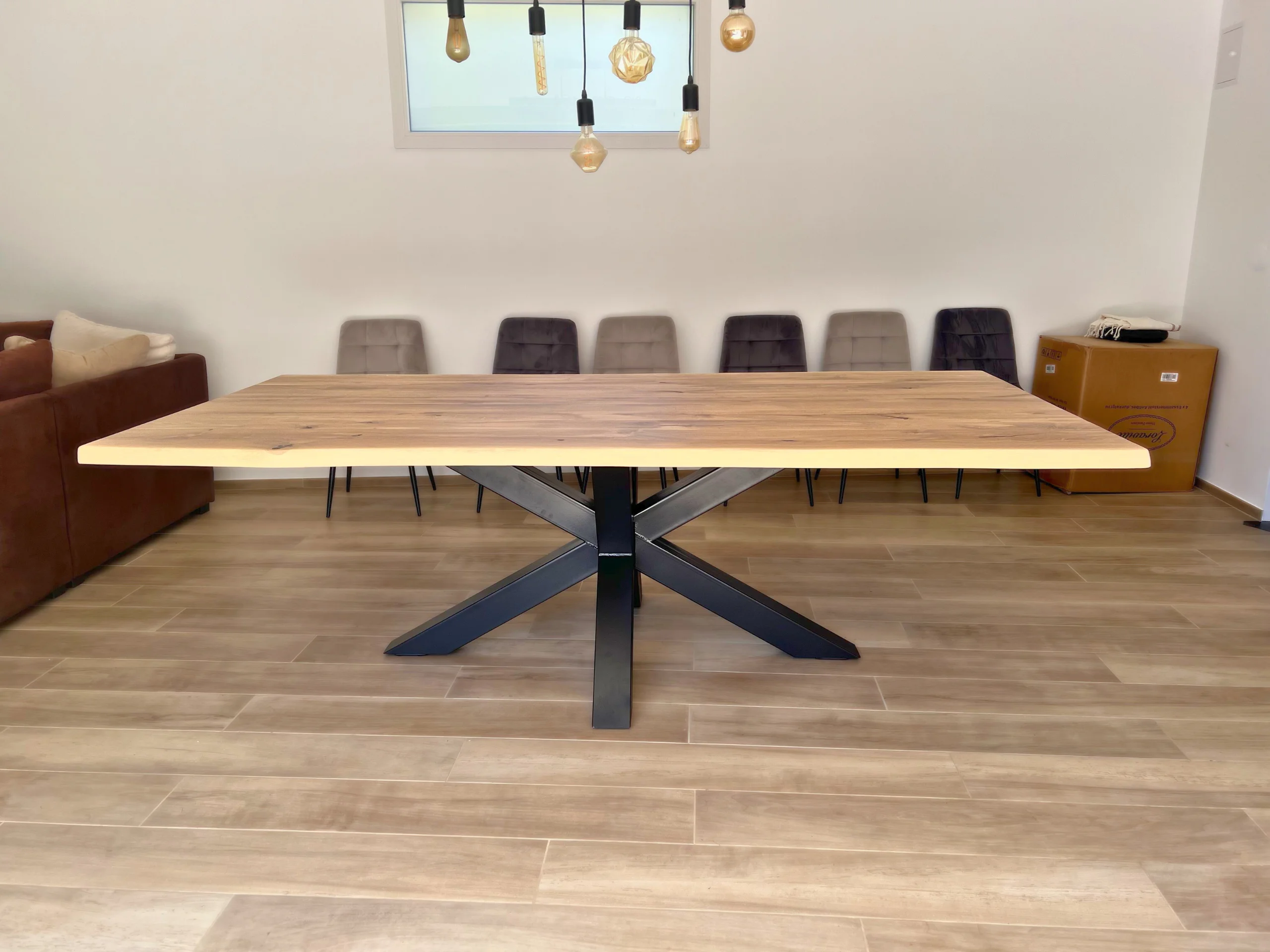 Un salon avec un luminaire, des chaises, et un pied de table industriel robuste Etoile qui soutient un grand plateau