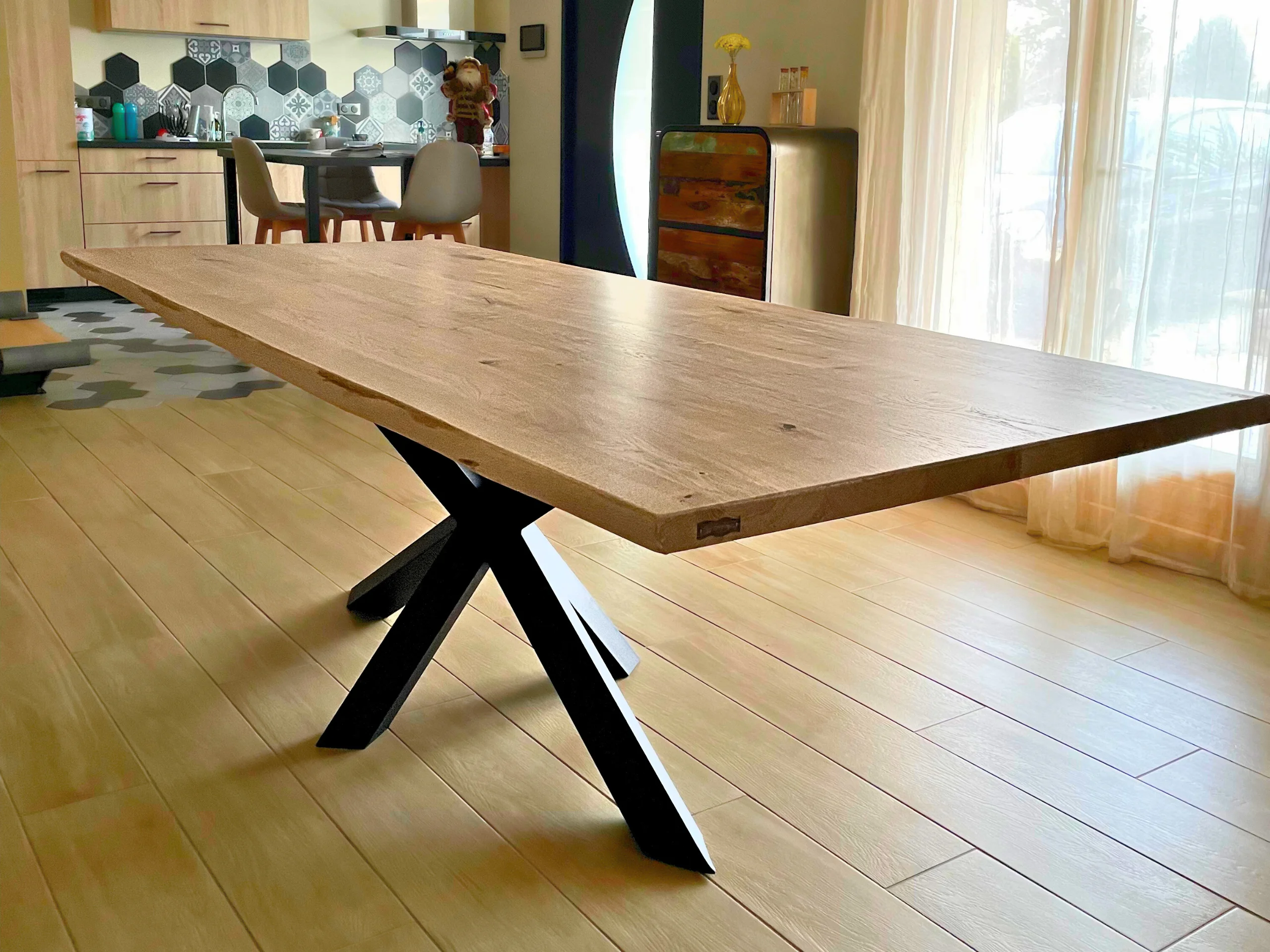 Une table avec un plateau en chêne clair et un pied central Etoile en acier cuit dans une salle à manger