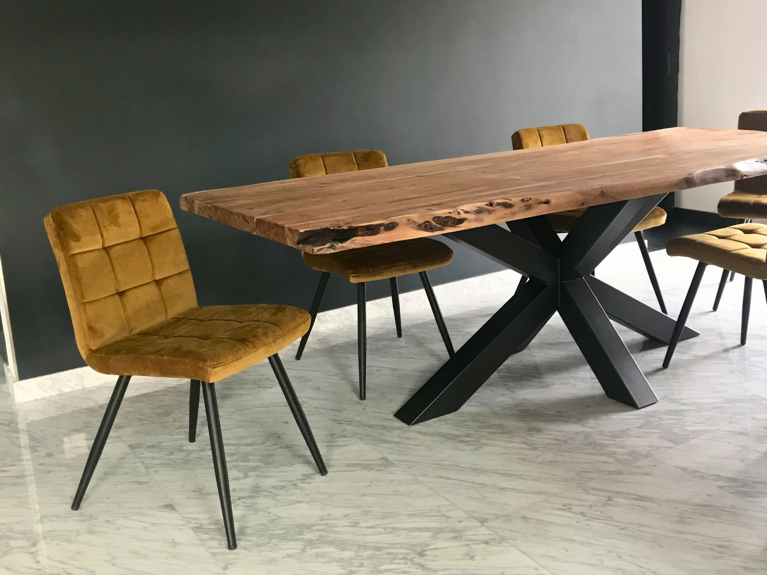 A living room with a table that has a star base, with yellow chairs
