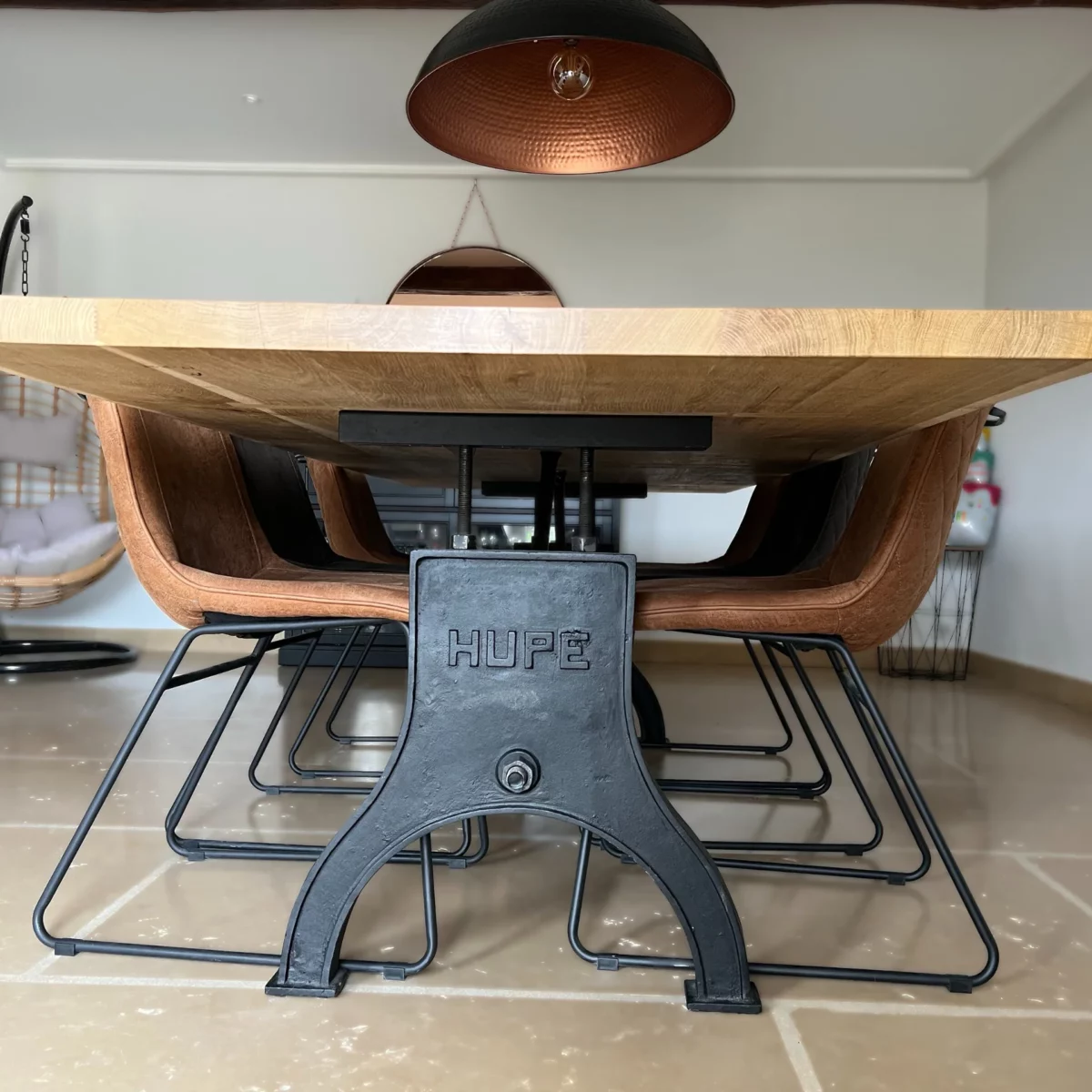 Une table avec des chaises, au premier plan un pied de table industrielle en fonte marqué HUPE