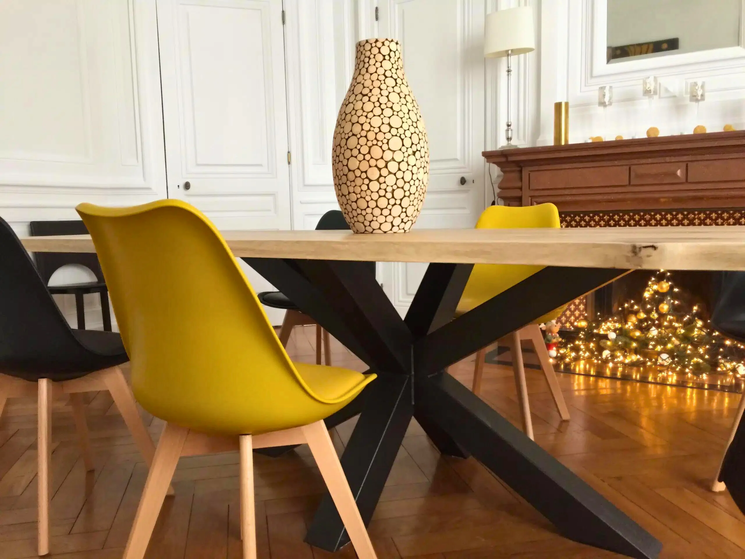 Une table avec un pied en forme d'étoile, des chaises, et un vase